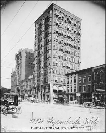Black-and-white photo of the Wyandotte Building in Columbus, Ohio, circa early 1900s, with horse-drawn carriages and pedestrians on the street.